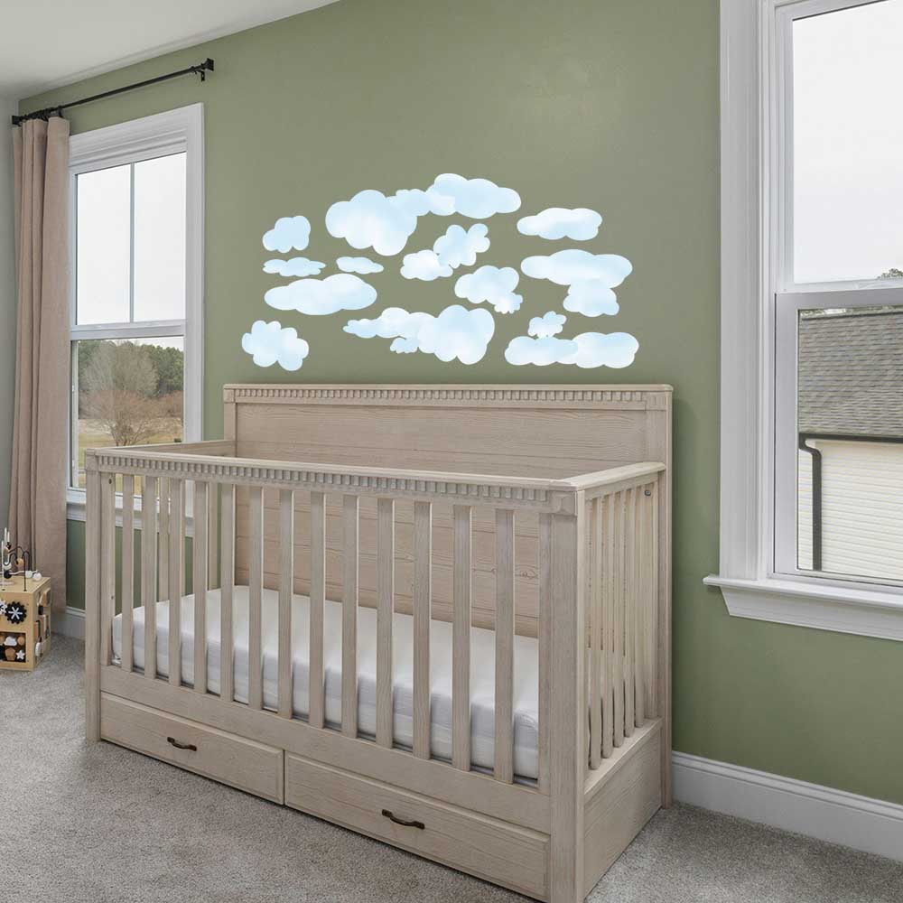 Nursery room with a crib and cloud wall decal on a green wall.