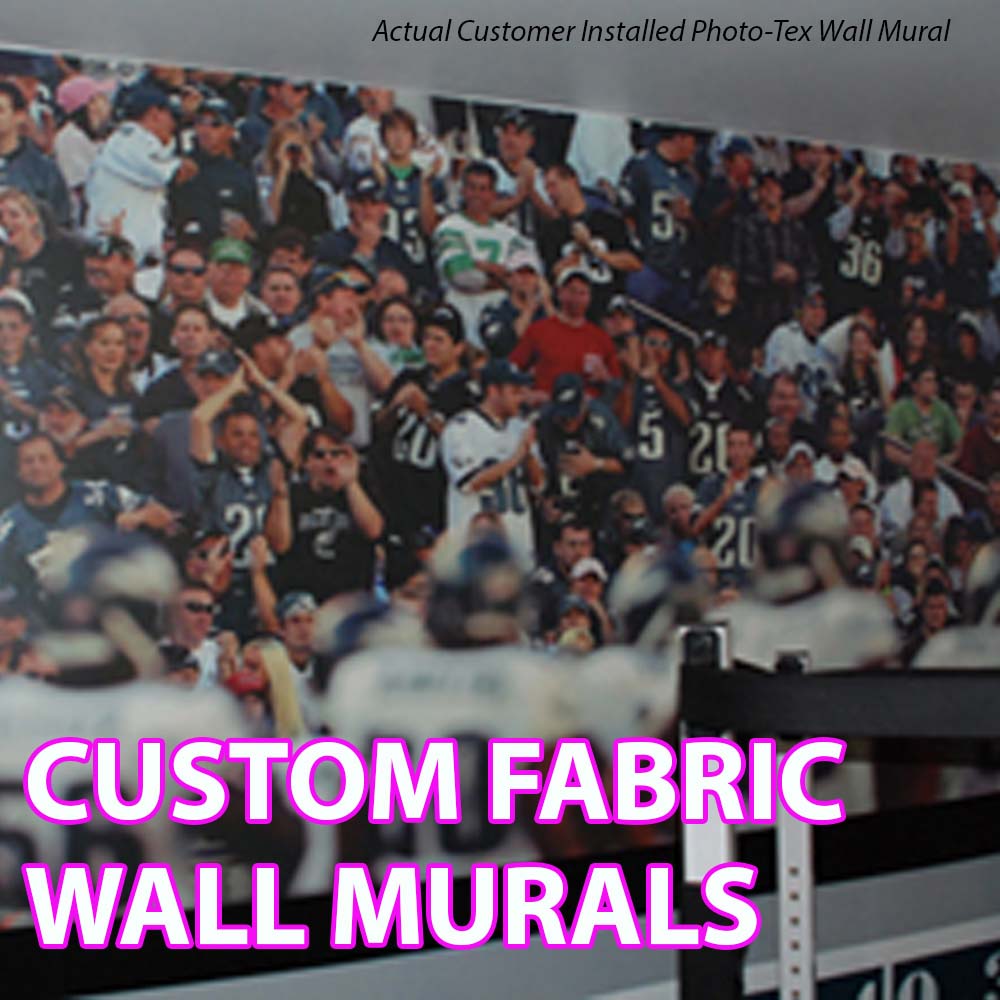 A large printed wall mural showing a crowded stadium crowd scene, with bold pink text reading 'CUSTOM FABRIC WALL MURALS' overlaid at the bottom. The top text says 'Actual Customer Installed Photo-Tex Wall Mural.