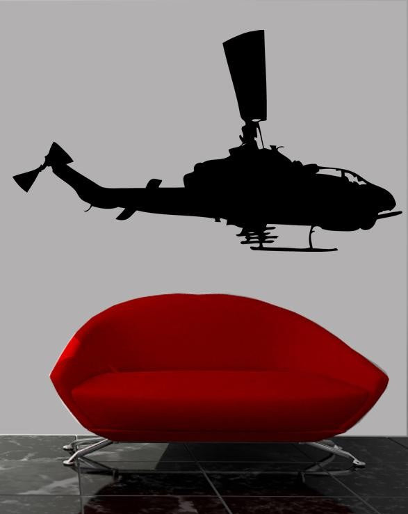 A black Apache helicopter silhouette wall decal displayed on a light gray wall above a modern red curved sofa with chrome legs.