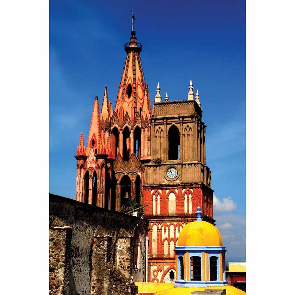 Tall colorful Mexican cathedral with an orange spire against a blue sky gloss poster printed | Wallhogs